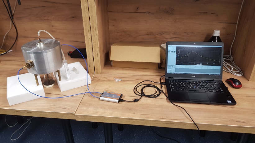 Measurements of electromagnetic properties of substances. The photo on the left shows a resonator with a beaker containing the tested substance placed underneath. The substance is sucked and transferred to the resonator, which changes its parameters under the influence of the tested substance. During the measurements, the electric permeability of the substance and its loss factor were checked.